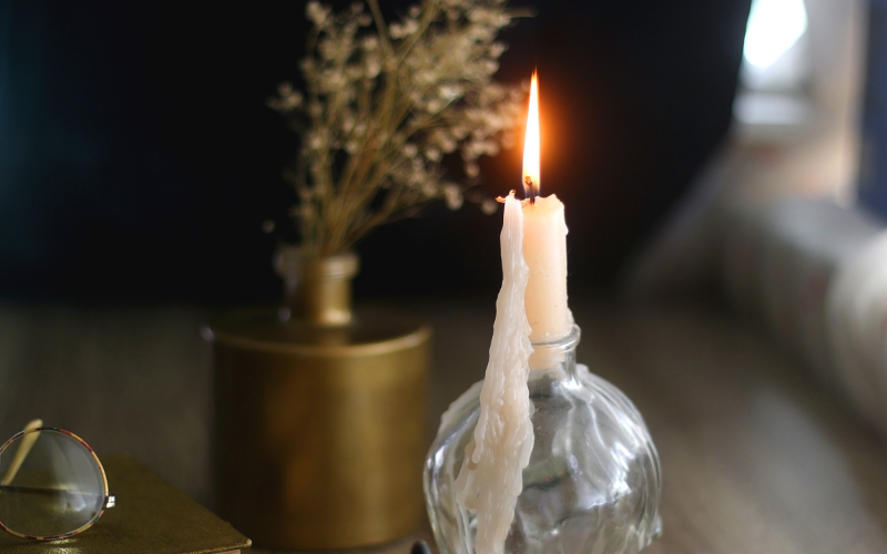 Lit candle with melted wax dripping down its side