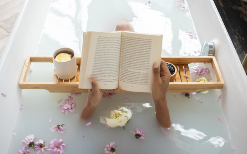 Woman soaking in a bath, reading a book