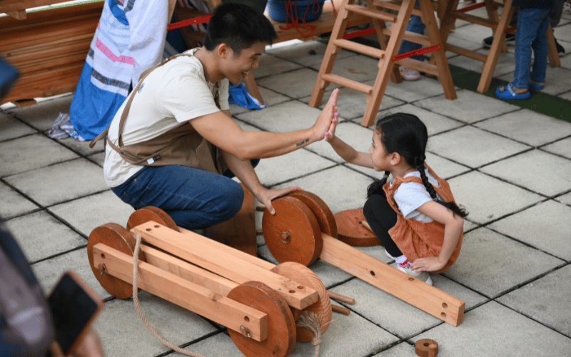  A male adult is seen giving high-five to a young girl