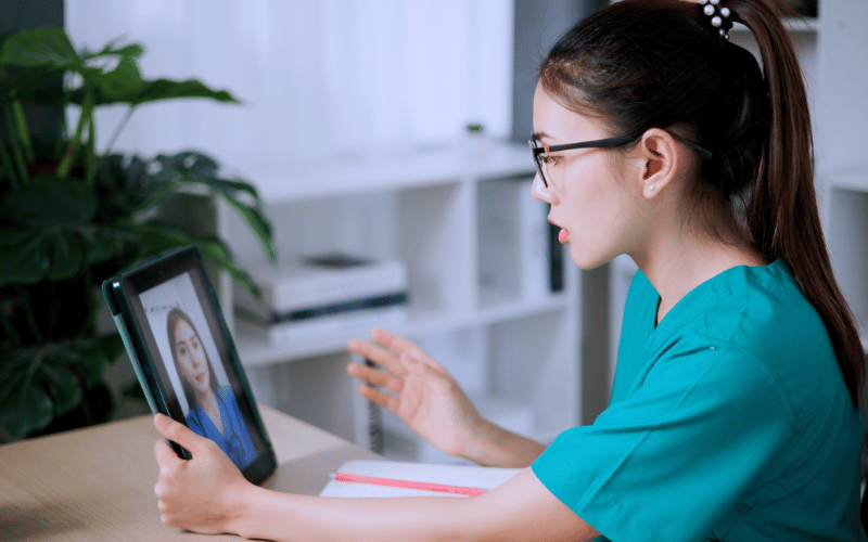Nurse conducting a telehealth consultation with a patient via tablet in a home or clinic setting.