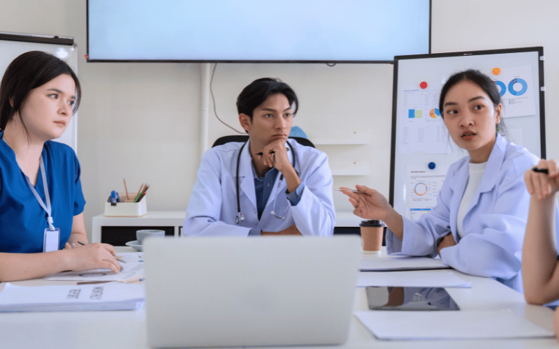 Healthcare team in a meeting room discussing digital health strategies with a laptop and charts.