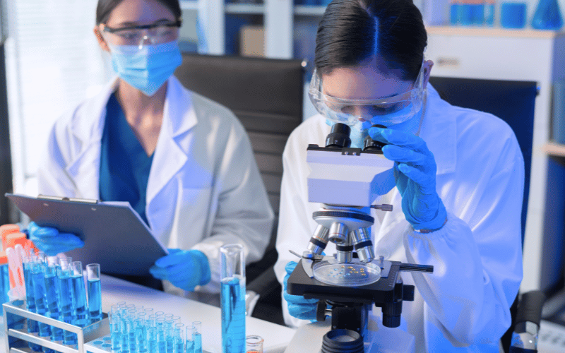 Lab technicians wearing masks conducting microscope and test tube analysis