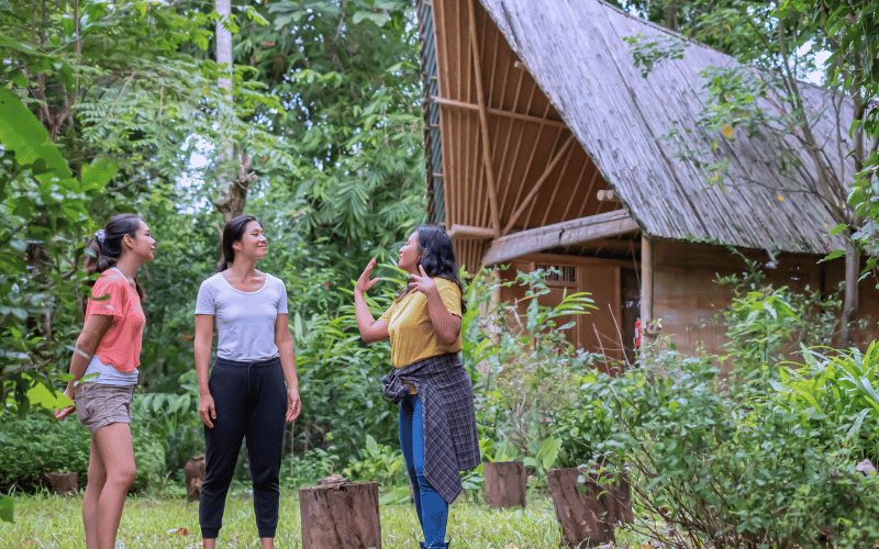 Women exploring eco-lodge architecture in a rural setting.