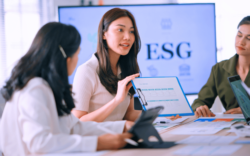 Two women reviewing ESG data on a laptop in a professional meeting environment