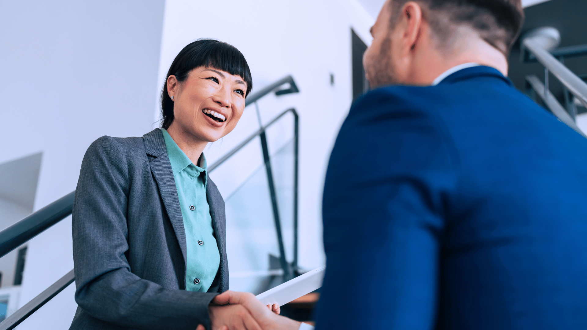 Asian lady shakes hand with a white guy