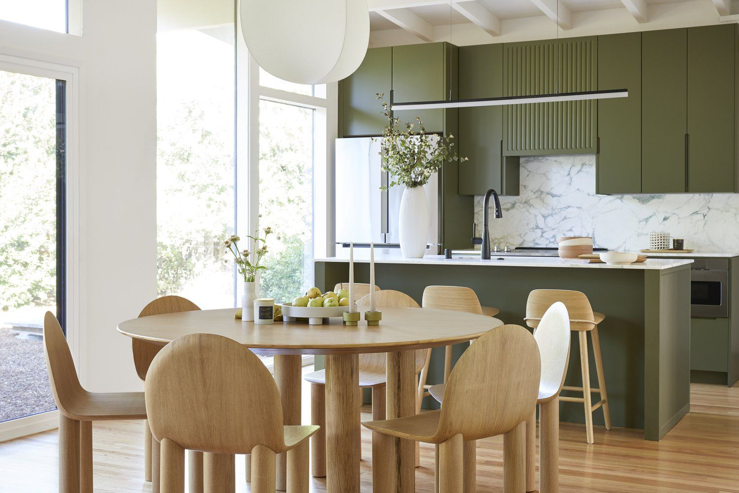 Clean lines, natural textures, and olive tones create a calming Japandi-inspired kitchen and dining area