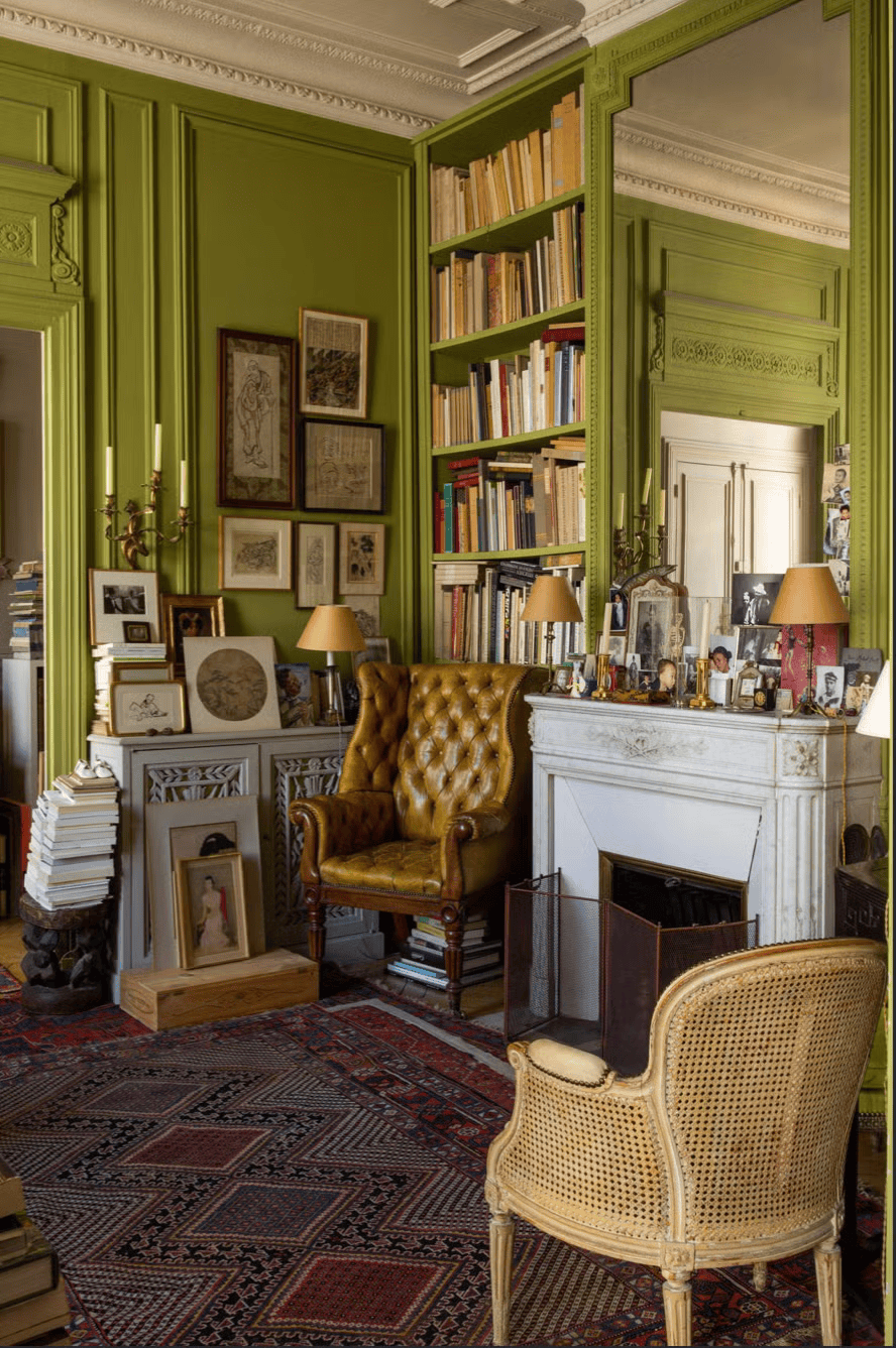 A richly layered reading nook full of character, where antique details meet lime green walls and overflowing bookshelves
