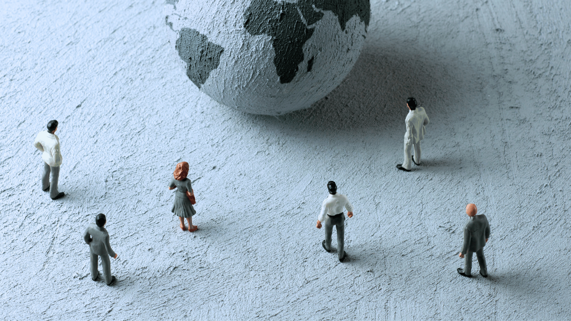 Corporate figurines standing in front of a globe