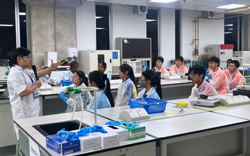 Students in lab coats listening to instructions during a science workshop
