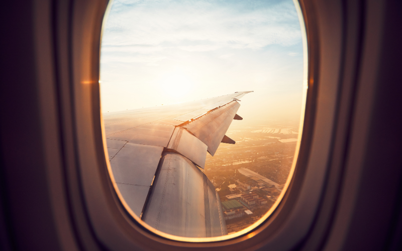 A view of an aeroplane wing and the sky through a window