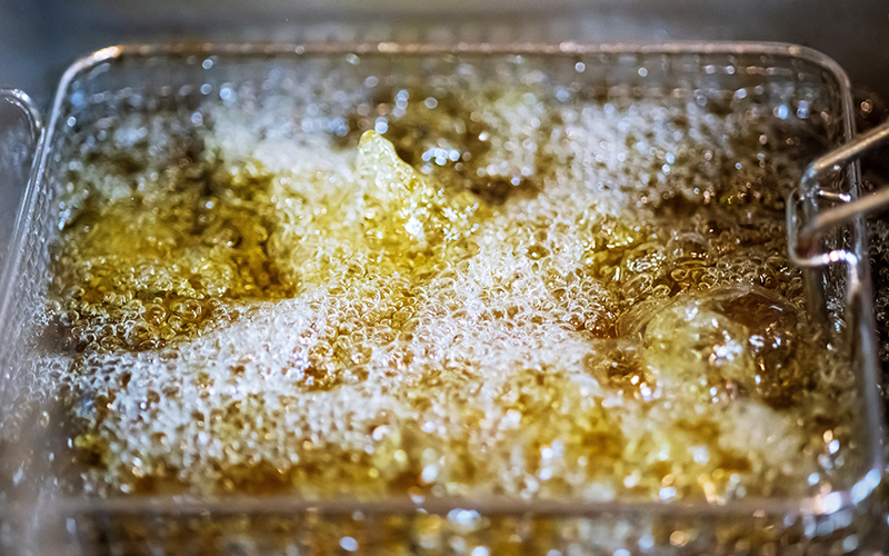 Deep fryers with hot bubbling boiling oil on restaurant kitchen