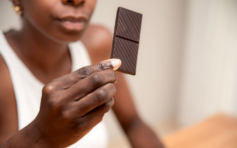 A woman holding up a piece of dark chocolate