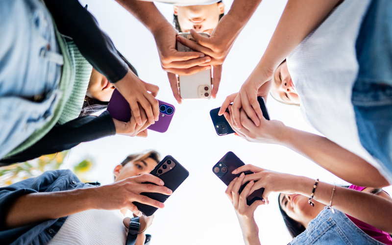 A group of people standing in a circle, each holding a smartphone and looking down at their screens