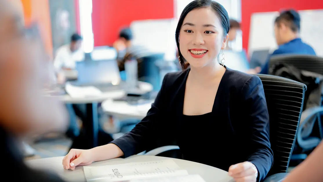 A lady is all smile at her seated place. 