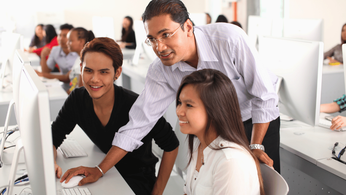 Lecturer guiding two students at the desktop learning