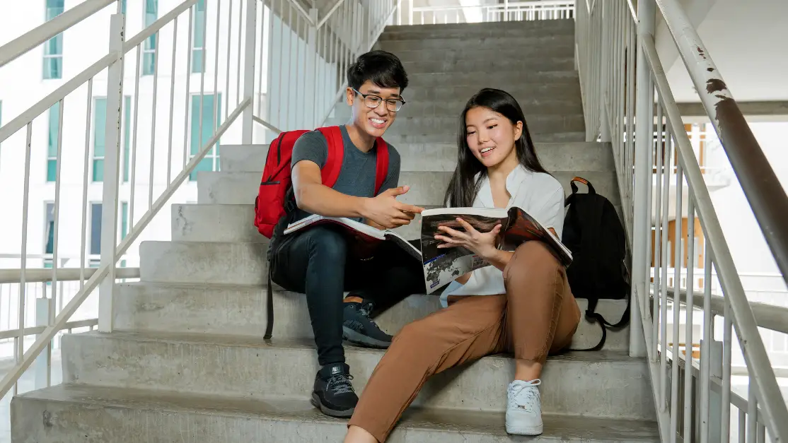 Students looking at textbook by the staircase