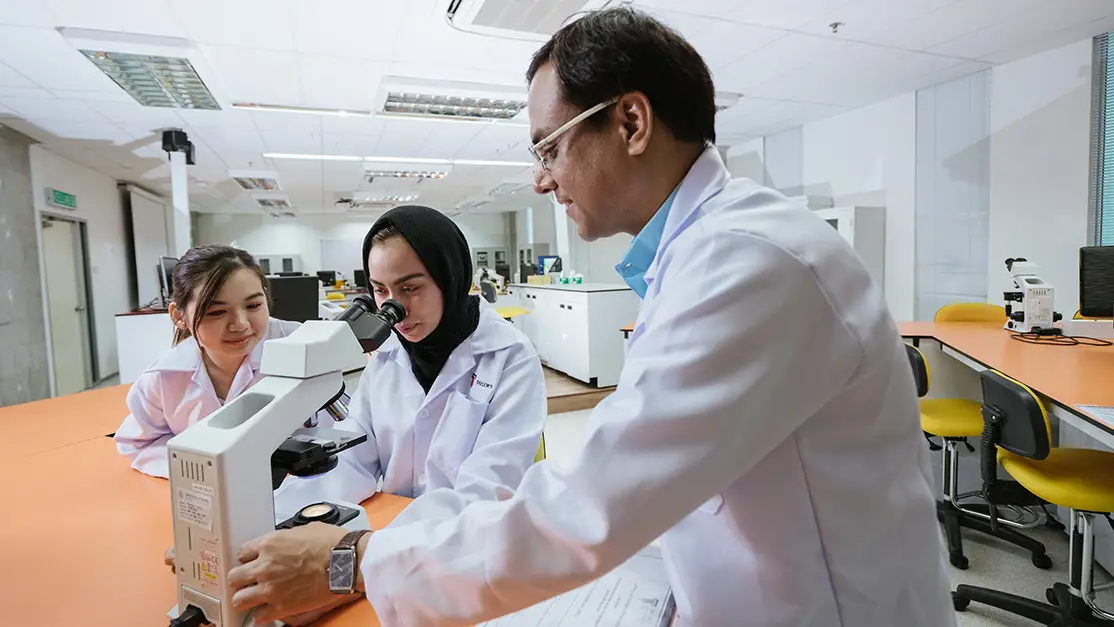 Lecturer guiding a student with microscope
