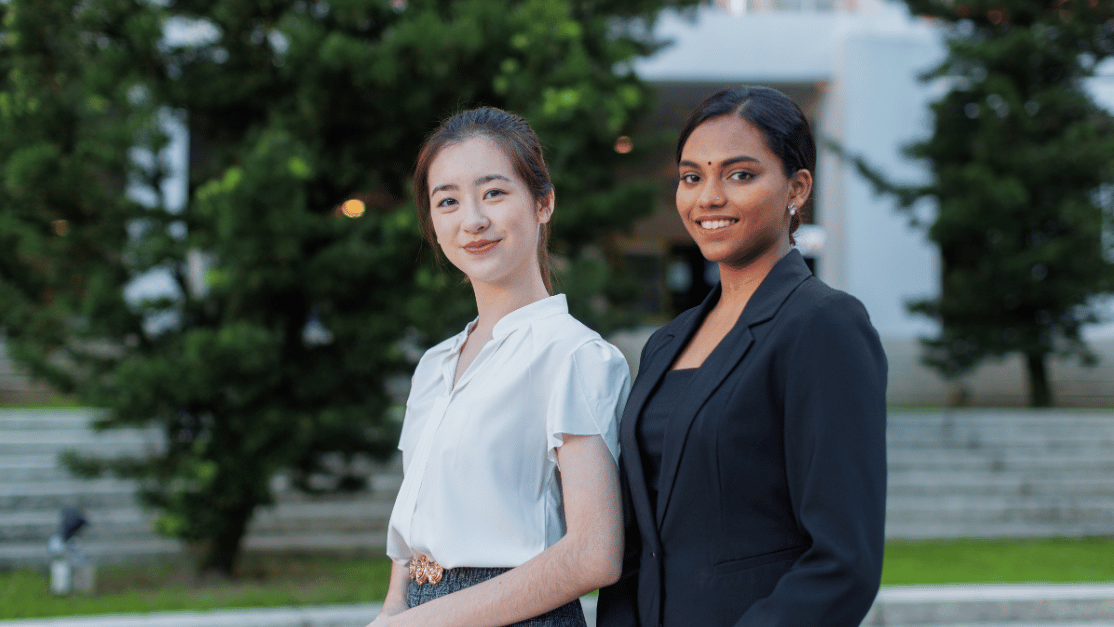 Two ladies smiling confidently in front of camera