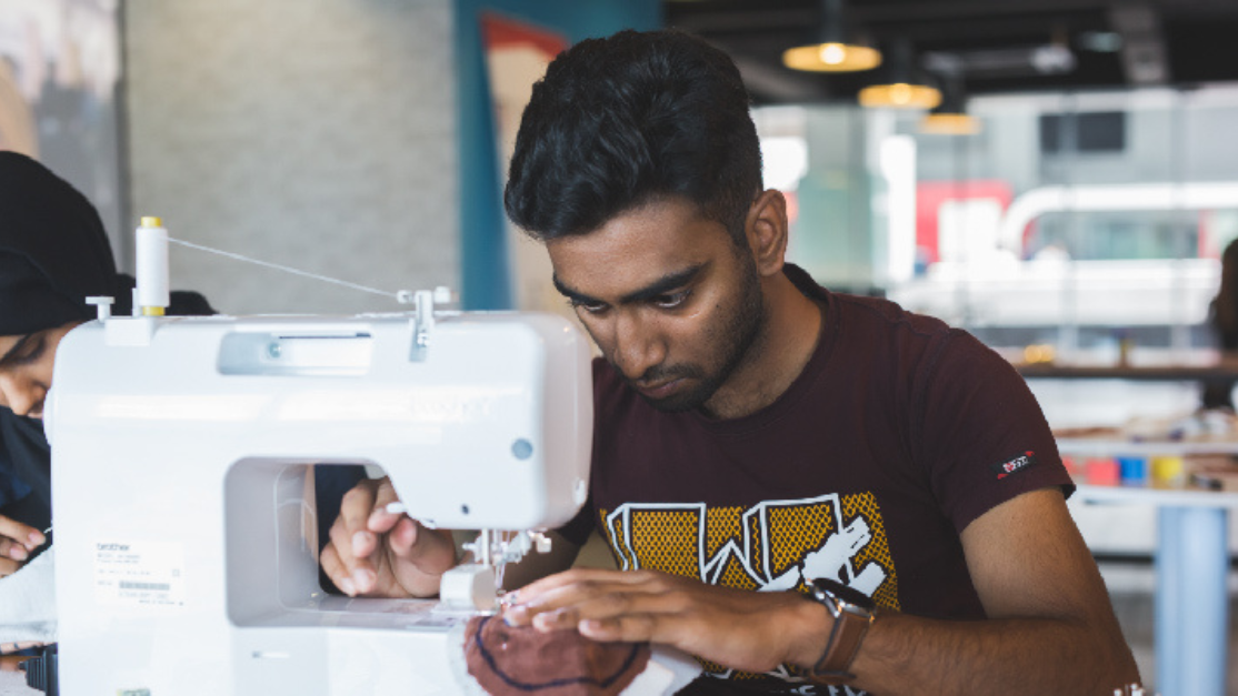 student sewing cloth using sewing machine