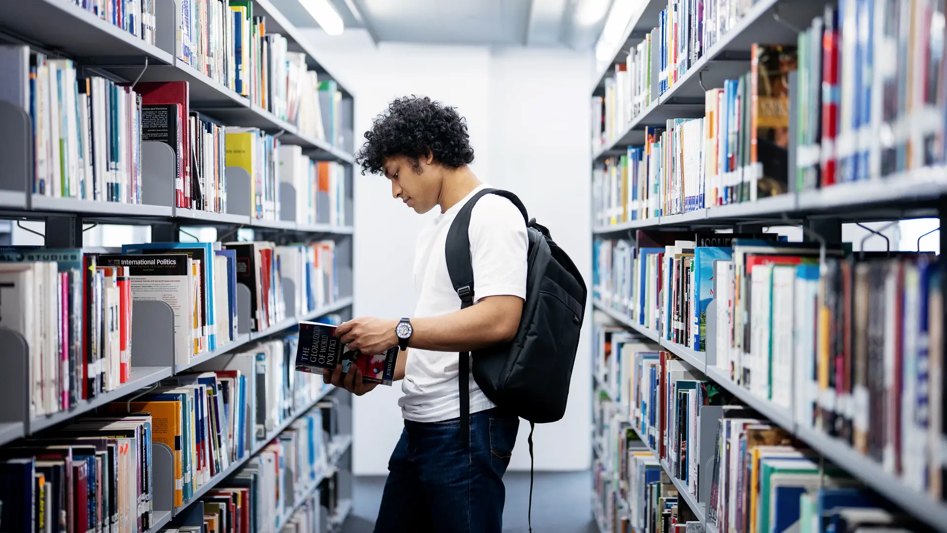 Afro-haired student checking out a book in the library