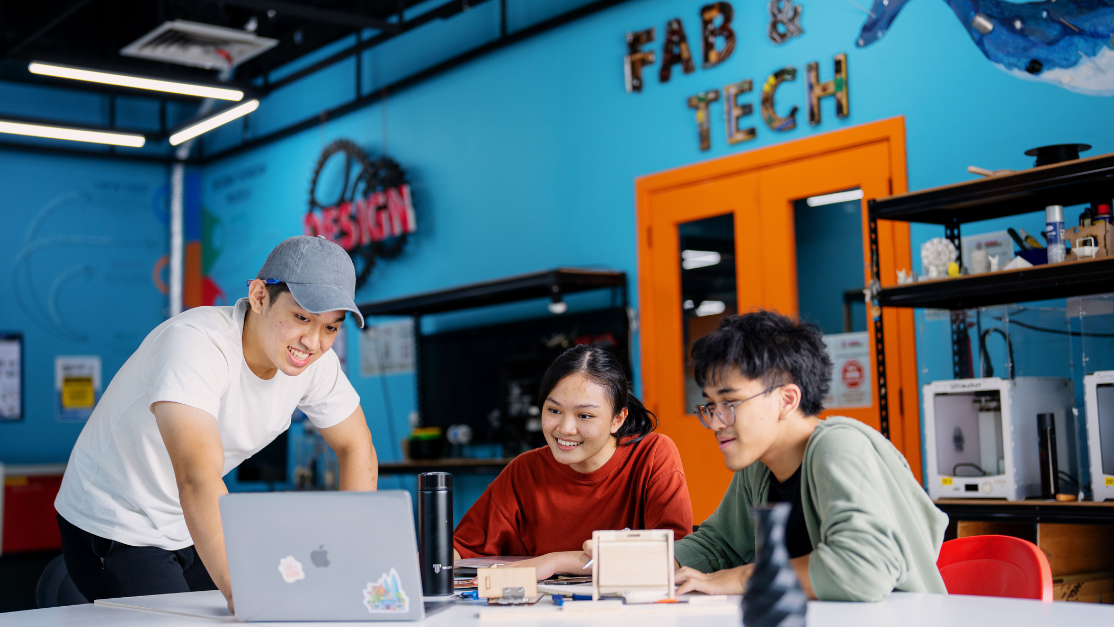 a student showing the other 2 students something in the laptop