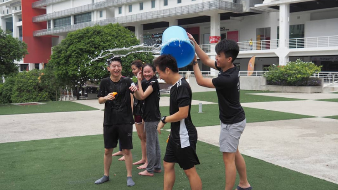 student pours a bucket of water over another student
