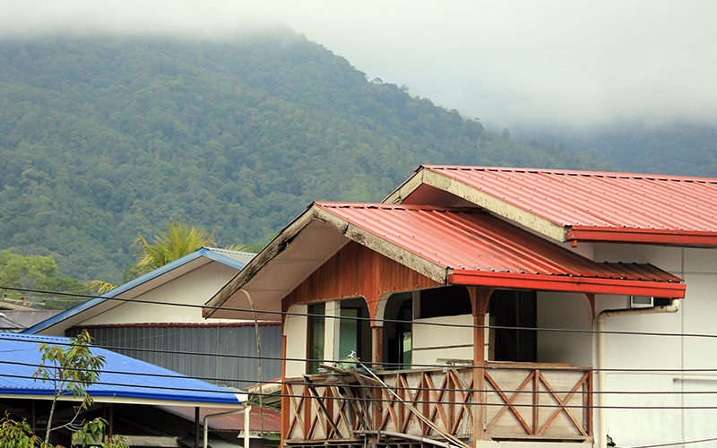 Traditional Wooden House with Red Metal Roof in a Misty Mountain Village