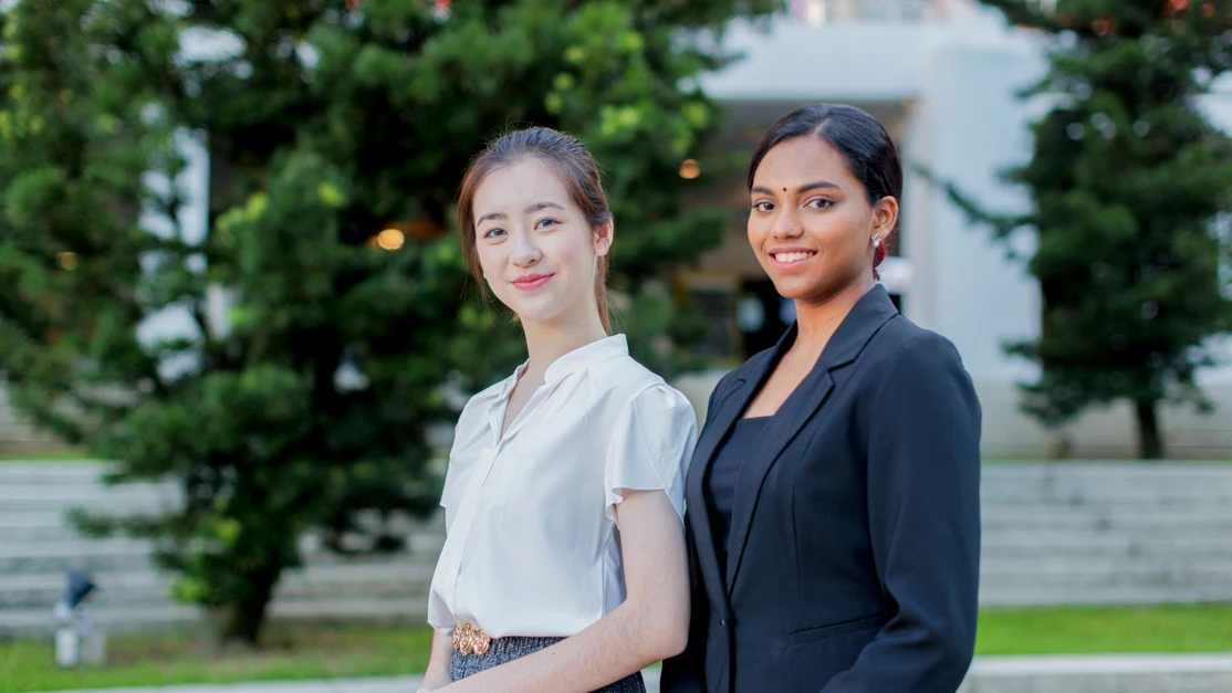 Two ladies smiling confidently in front of camera
